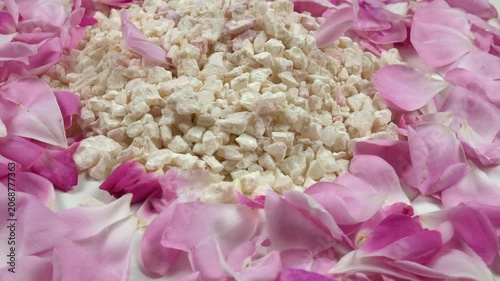 Heap of relaxing rose bath salt with use rose essential oil, fresh pink rose petals are on a white table, background, side view