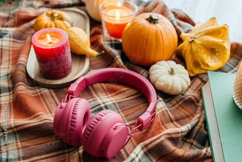 Autumn mood with headphones, book, candles, and plaid blanket