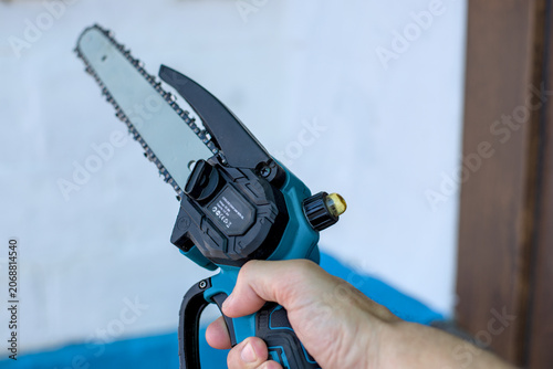 Photo of mini chainsaw in male hand
