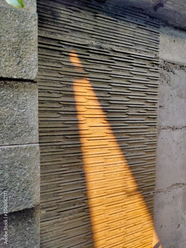 Sunlit grooves on concrete wall with warm shadow play