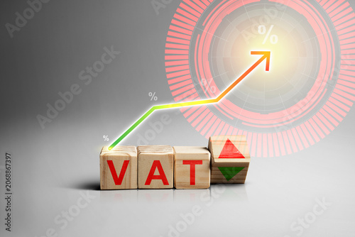 Wooden blocks spelling VAT with an upward pointing arrow, symbolizing value added tax increase, inflation, and fiscal policy changes