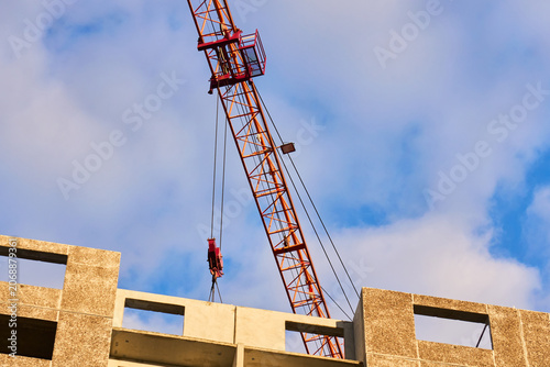 Orange tower crane jib with trolley and pulleys in action
