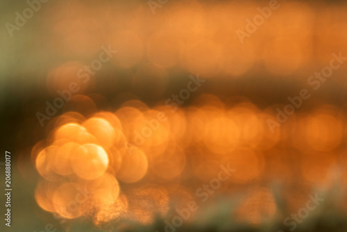 Burred sunset reflections on water creating golden sparkles
