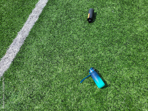 Two bottles of water are lying on the green football field