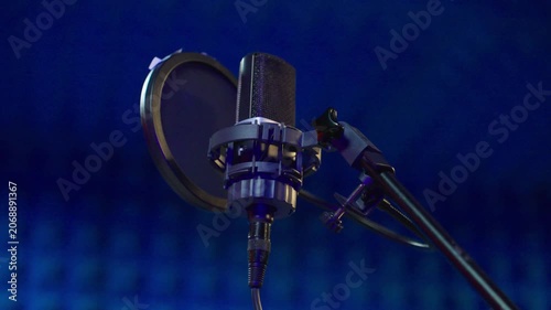 Condenser microphone setup poised midleft with pop filter under blue studio lighting ready