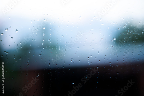 Fotografie Raindrops covering a window glass surface during inclement weather, creating a w