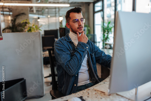 Vászonkép Young businessman thinking and concentrating on computer