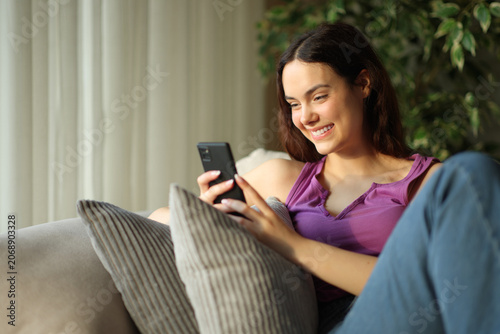 Happy teenage girl using smart phone at home