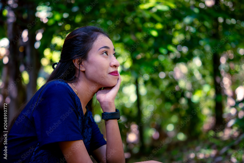 Fototapeta premium A young woman rests thoughtfully in a green forest.