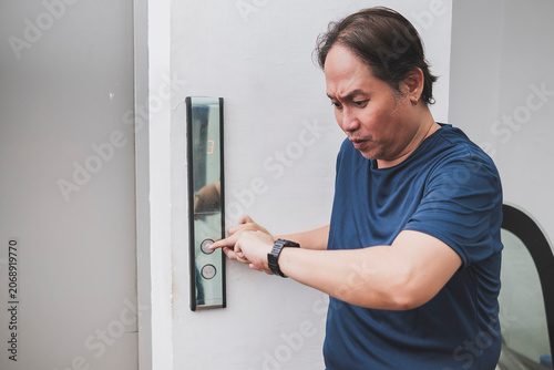 Fotografie Southeast Asian office worker repeatedly checks the elevator while worried about being late for work or a meeting
