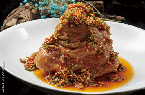 Sichuan-style braised pork knuckle served on a round white porcelain plate