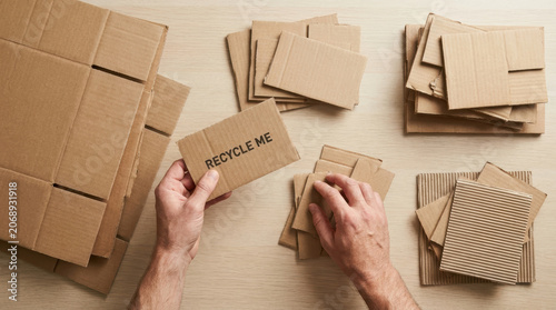 Cardboard recycle hand paper waste sorting corrugated scrap on wood table with eco friendly reuse concept
