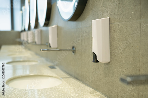 Fotografie modern soap dispenser mounted on wall in public restroom with multiple sinks