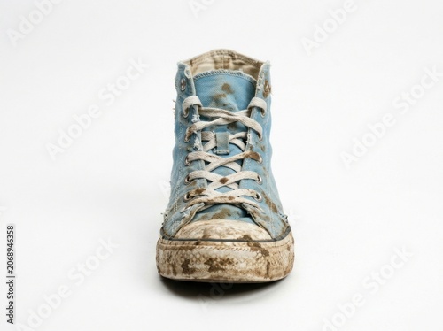 Grimy blue canvas footwear centered on a seamless white background in sharp studio focus for sanitation or humanitarian marketing
