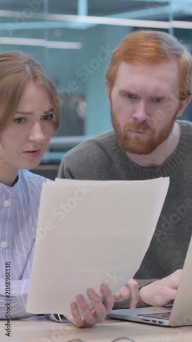 Young Man and Woman Reading Documents while using Laptop, Vertical Video