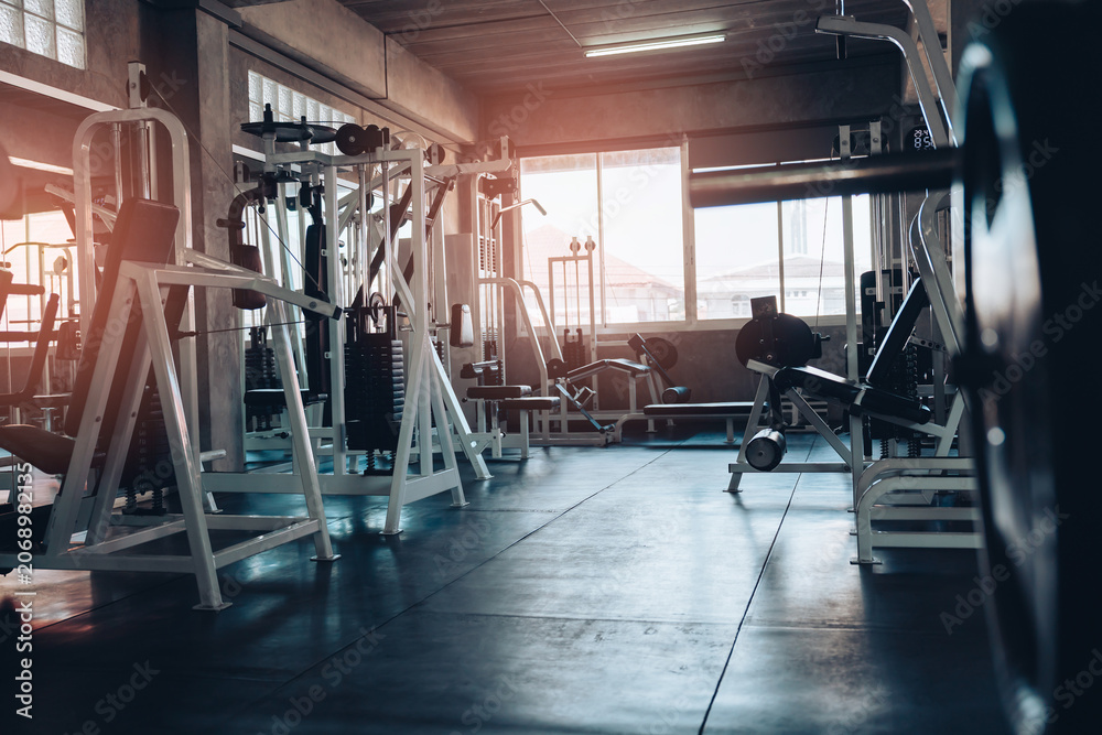 Obraz premium fitness concept. Fitness gym interior with exercise machine and weight bench in sunlit room