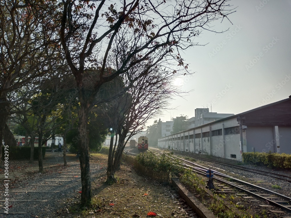 Fototapeta premium Vintage train on railway tracks at sunset with trees and buildings