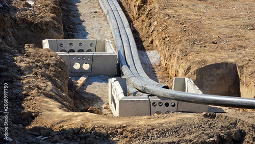Flexible high voltage power cable conduits routed through precast concrete utility chambers in open trench