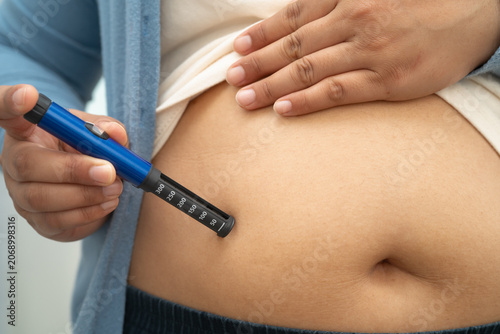 Bild auf Leinwand Asian woman injecting herself diabetes injecting insulin in stomach at home