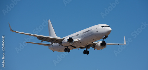 The plane lands, passenger airliner. The plane lands. Airplane, passengers flying in the blue sky, preparing to land at the airport