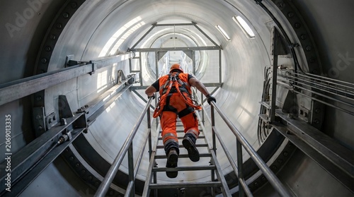 Worker in protective gear inspecting underground tunnel infrastructure.