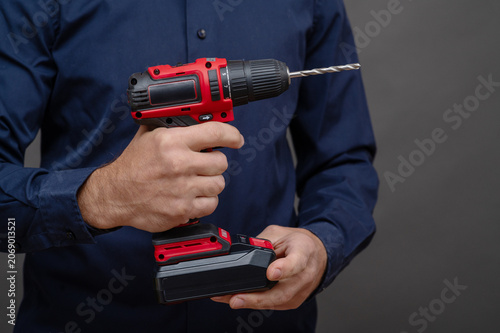 Cordless drill held with both hands. drill tool prepared for drilling task, cordless drill emphasizing control and precision, repair and construction concept, closeup detail, isolated dark background