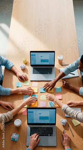 Business professionals collaborating with laptops and sticky notes at office worktable