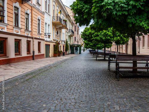 Street view in Chernivtsi, Ukraine, showing buildings and trees with green leaves on a quiet day