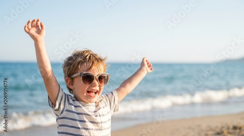 Happy boy with arms raised wearing sunglasses on tropical beach