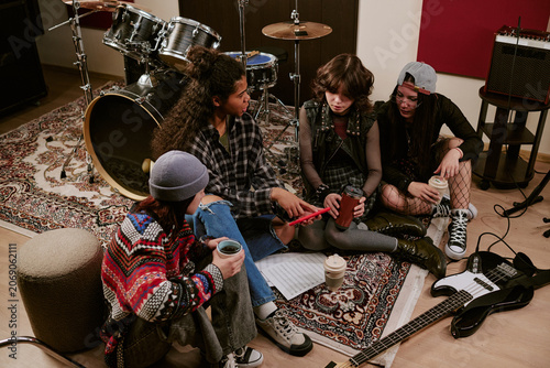 Schilderij op canvas High angle shot of diverse teenage girls music group planning rehearsal on studio floor, reviewing notes and instruments