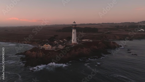 Cuadro en lienzo Lighthouse on rocky coast at sunset with ocean waves