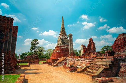 Ancient headless Buddha statues lining the red brick wall at Wat Mahathat in Ayutthaya, Thailand.