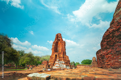 Ancient headless Buddha statues lining the red brick wall at Wat Mahathat in Ayutthaya, Thailand.