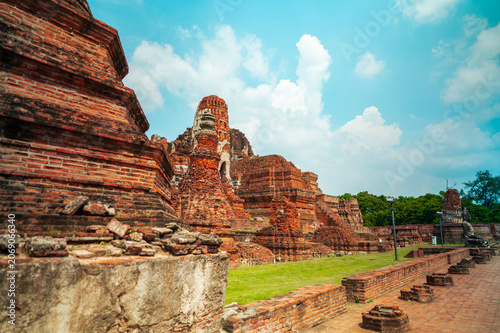 Ancient headless Buddha statues lining the red brick wall at Wat Mahathat in Ayutthaya, Thailand.