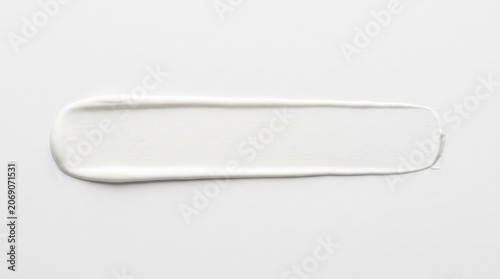 White cosmetic cream smear on white background. Smooth lotion texture swatch for beauty skincare branding.
