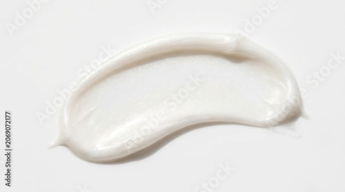 White pearlescent cosmetic cream smear on white background. Smooth shimmering lotion swatch for skincare beauty product.