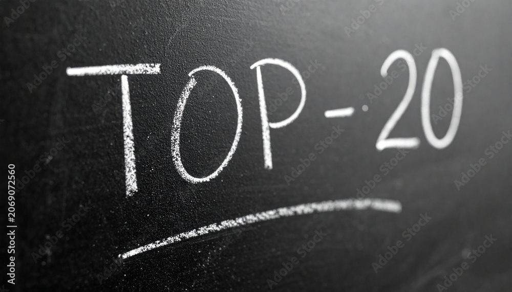 Fototapeta premium Textured black chalkboard with text TOP 20 written in white chalk. Close-up.