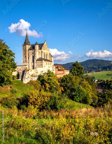 Historic Stone Church Standing on Green Hillside in Sunny Rural Landscape