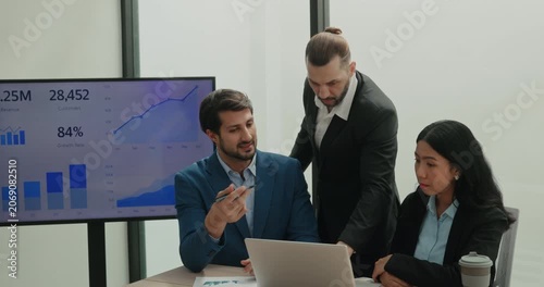 Portrait of multiracial business experts analyze financial data on laptop in office. Corporate managers team plans profit of deals against screen with charts