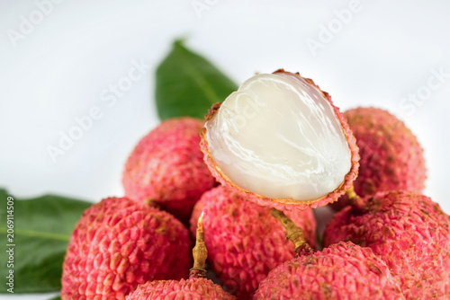 Close up of fresh red litchi or lychee with cut in half slice isolated on fruit background. Juicy lychee fruit with red skin, white flesh and green leaves, concept of tropical sweet fruits.