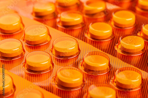 Yellow tablets sealed in orange blister packs in close up view. Healthcare and pharmaceutical concept for medication, treatment, dosage, and packaging.
