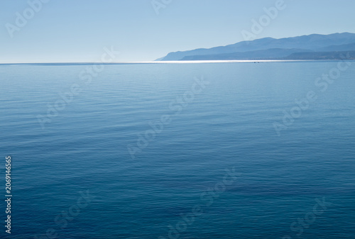 Calm blue sea around the island of Crete in Greece in Europe with hazy mountains in the distance in the background.