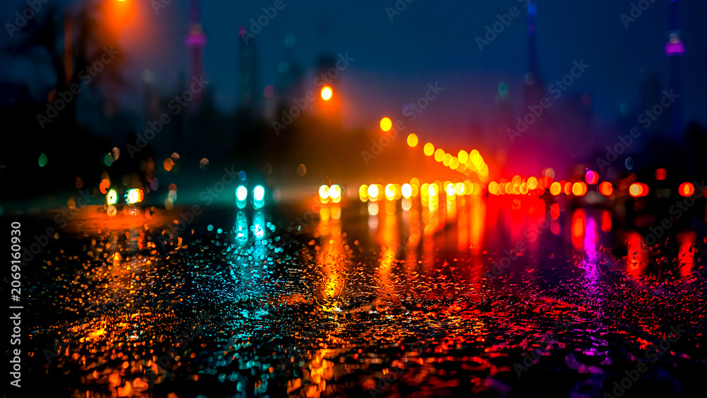 Fototapeta premium 雨の夜の街で濡れた路面に反射する色鮮やかな光の玉ボケ