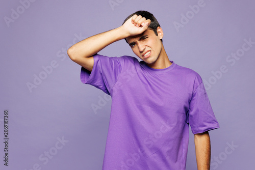 Εκτύπωση καμβά Young sad sick ill tired Caucasian man wear violet t-shirt casual clothes put hand on forehead suffer from headache isolated on plain pastel light purple background studio portrait