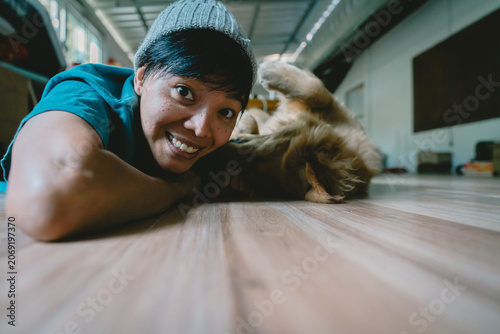 A real Asian man takes a selfie with a year-old golden retriever. The dog is licking its owner's face. Smiling People and fun playing together looking happily at the camera at home Pet and person