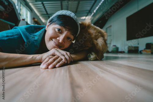 A real Asian man takes a selfie with a year-old golden retriever. The dog is licking its owner's face. Smiling People and fun playing together looking happily at the camera at home Pet and person