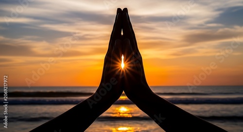 Hands in prayer position silhouetted against a beautiful sunset over the ocean
