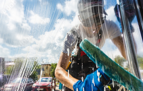 Фотография Professional window cleaner using an applicator to wash glass with suds