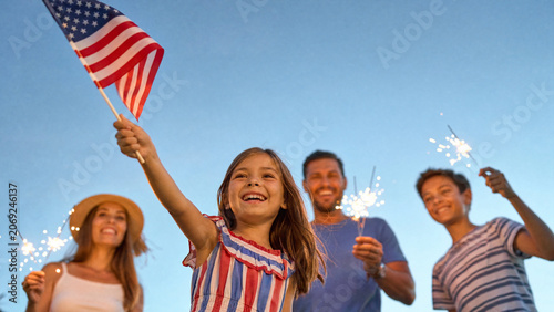 Happy family celebrating Independence Day with American flag and sparklers at twilight, patriotic summer holiday and fourth of july celebration for childhood and parenting