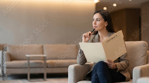 Focused businesswoman reading a contract in a modern office lounge, AI technology concept for business strategy and corporate planning